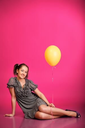 cute girl holding balloons over pink backgroundの写真素材