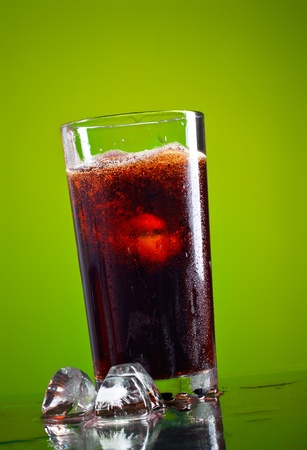 glass of cola with ice on green backgroundの写真素材