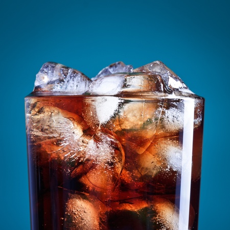 glass of cola with ice on blue backgroundの写真素材