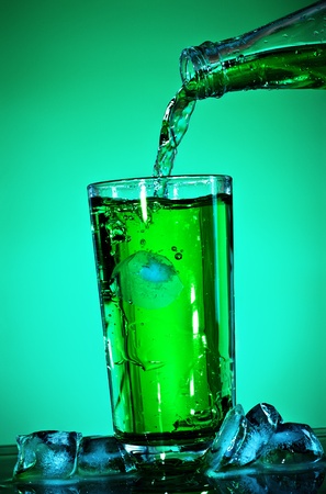 pouring soda in glass over green backgroundの写真素材