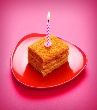 birthday cake with candle on pink backgroundの写真素材