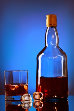 whiskey bottle and glass on blue backgroundの写真素材