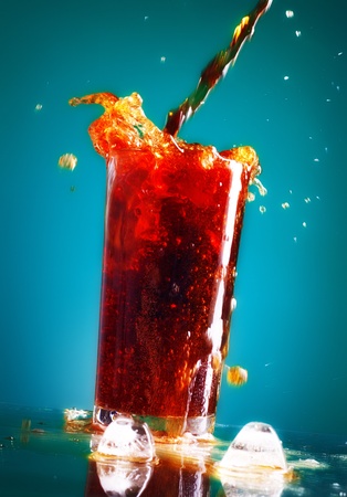 pouring cola in glass over blue backgroundの写真素材