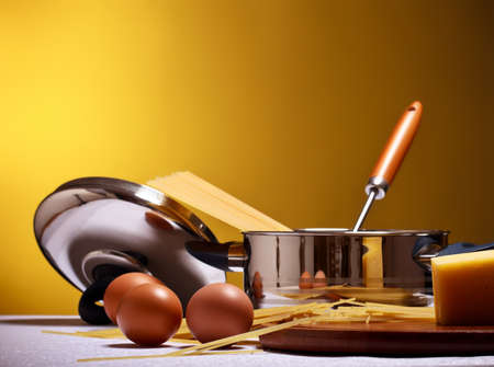 spaghetti, eggs, cheese and utensils on tableの写真素材