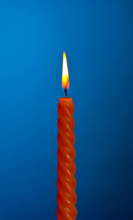 single twisted burning candle over blue backgroundの写真素材