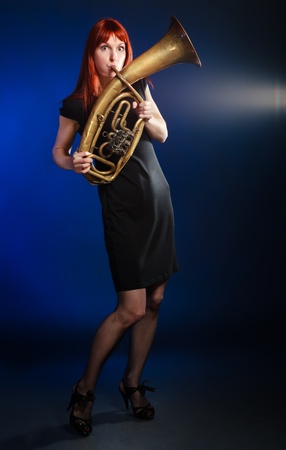 girl in black dress with trumpet, blue background