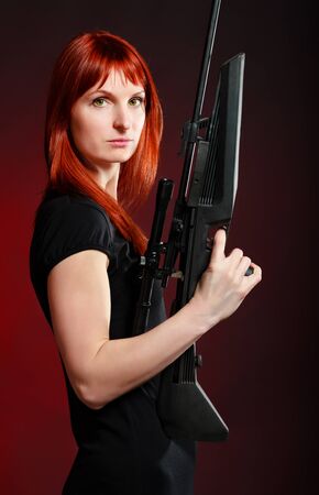 woman in black dress with sniper rifle, red backgroundの写真素材
