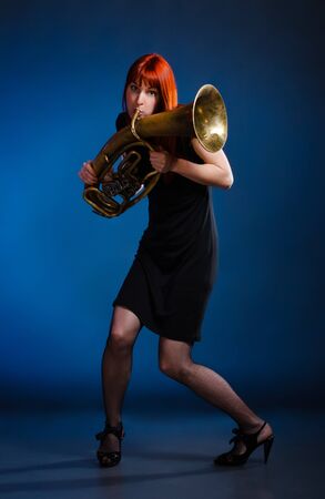 girl in black dress with trumpet, blue backgroundの写真素材