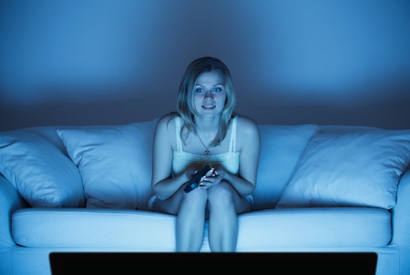 beautiful lonely woman sitting on couch and watching tvの写真素材