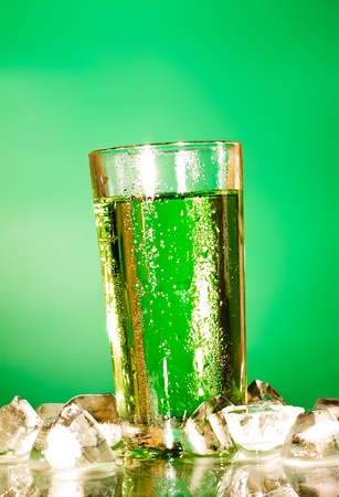 glass of soda with ice over green backgroundの写真素材