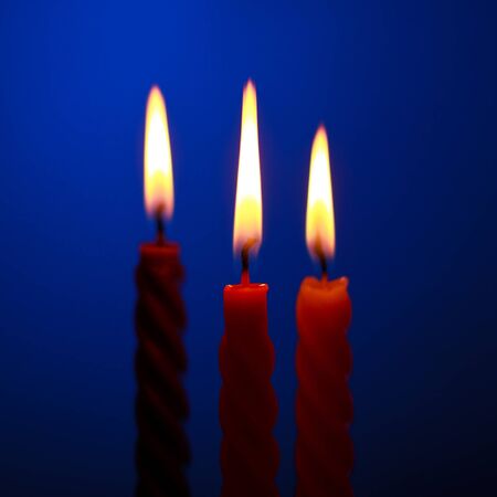 three twisted burning candles over blue backgroundの写真素材