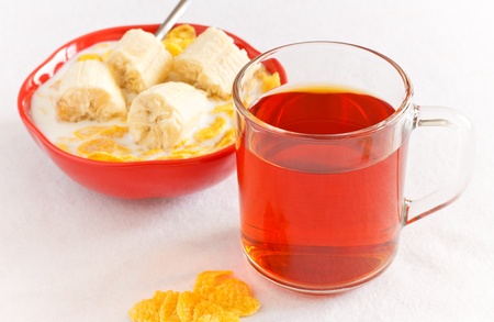 cornflakes with banana in bowl and teaの写真素材