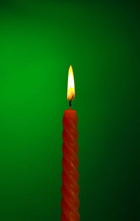 single twisted burning candle over green backgroundの写真素材