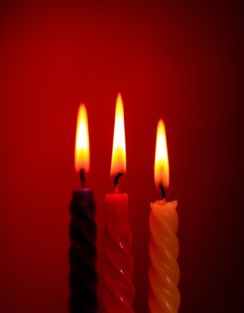 three twisted burning candles over red backgroundの写真素材