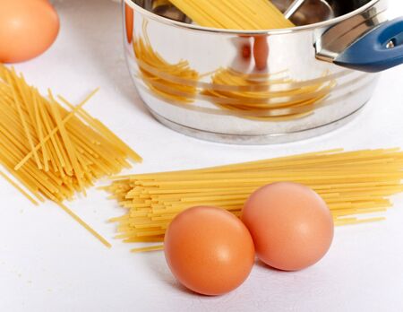 spaghetti, eggs and kitchen utensil on tableの写真素材