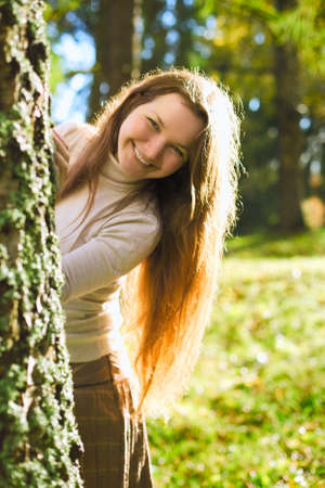 beautiful girl playing and hide for tree in autumn parkの写真素材