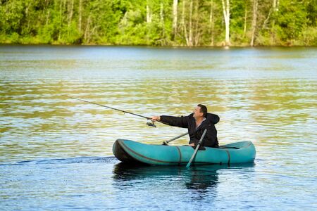 man fishing in rubber boat on a lakeの写真素材