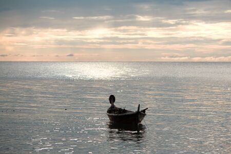 abandoned boat on waves under sunset, Andaman Sea, Thailandの写真素材