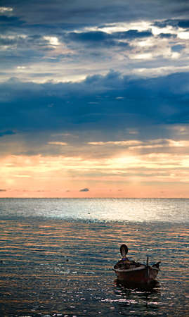 abandoned boat on waves under sunset, Andaman Sea, Thailandの写真素材