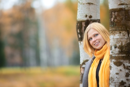 beautiful smiling blond girl in autumn parkの写真素材