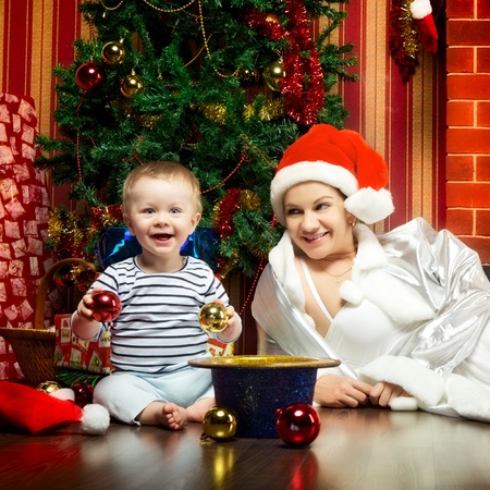 mother and baby sitting next christmas treeの写真素材