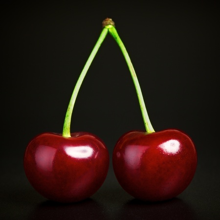 two fresh ruby cherries on black backgroundの写真素材