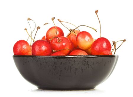 bowl full of cherries isolated on white backgroundの写真素材