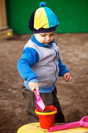 little boy playing in the sandbox at autumnの写真素材
