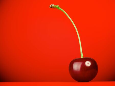 fresh red cherry with stem on red backgroundの写真素材