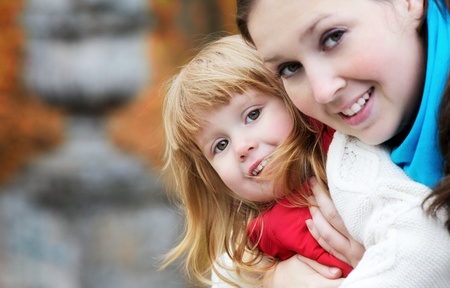 beautiful little girl and mother in autumn parkの写真素材