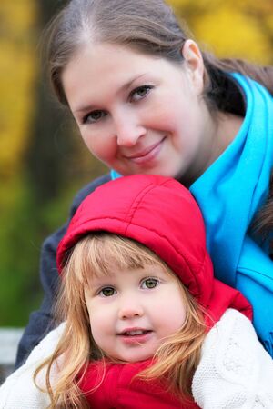 beautiful little girl and mother in autumn parkの写真素材