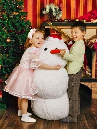two beautiful child and toy snowman near christmas treeの写真素材