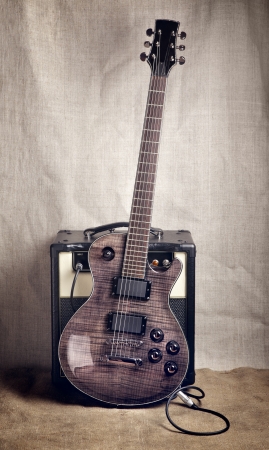 black electric guitar and amplifier on brown canvas backgroundの写真素材