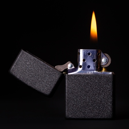 black gasoline lighter with flame on dark backgroundの写真素材
