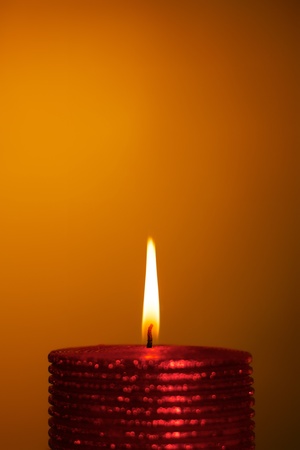 burning wax candle on a yellow backgroundの写真素材