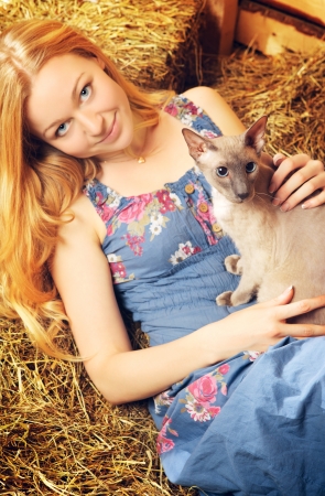 beautiful girl with cat on hayloft at summer dayの写真素材