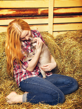beautiful girl with cat on hayloft at summer dayの写真素材