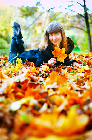 beautiful girl lying on a glade in autumn forestの写真素材