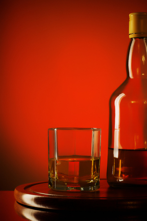 glass and bottle of whiskey on a red の写真素材