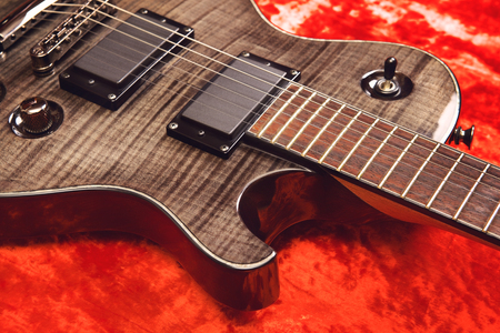 black electric guitar on red velvet backgroundの写真素材
