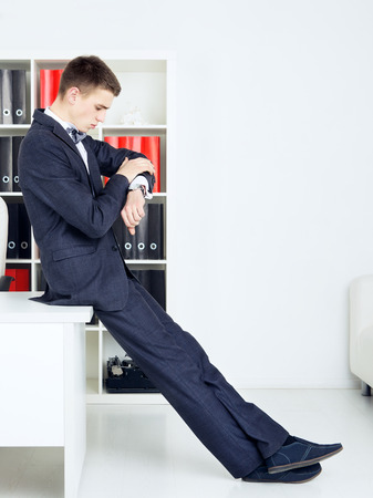 handsome businessman looking at watch in his officeの写真素材