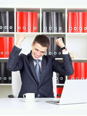 confident young businessman triumph looking at laptopの写真素材