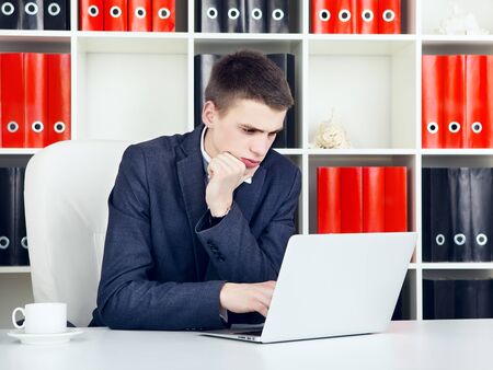 confident young businessman working on laptop in his officeの写真素材