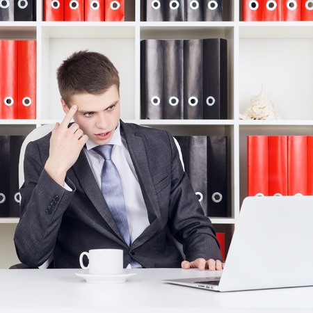 confident young businessman working on laptop in his officeの写真素材