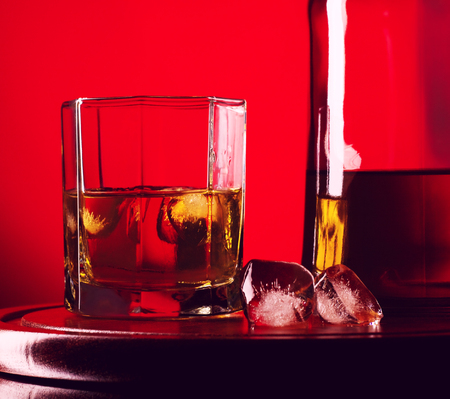 glass and bottle of whiskey on a red backgroundの写真素材