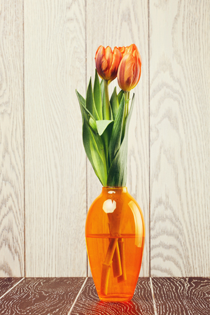 tulip flowers bouquet in vase on wooden backgroundの写真素材