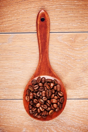 wooden spoon with coffee beans on tableの写真素材