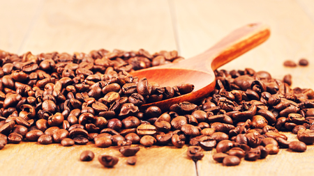 wooden spoon with coffee beans on tableの写真素材