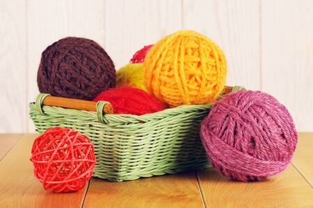 colorful yarn balls in wicker basket on wooden backgroundの写真素材