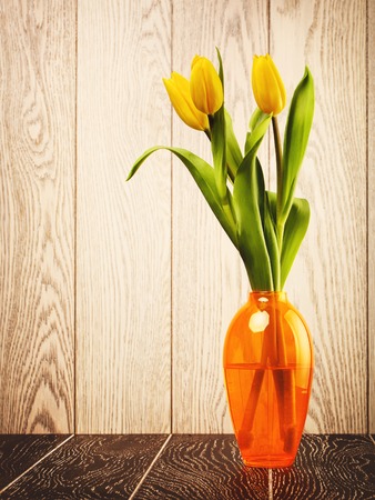 tulip flowers bouquet in vase on wooden backgroundの写真素材